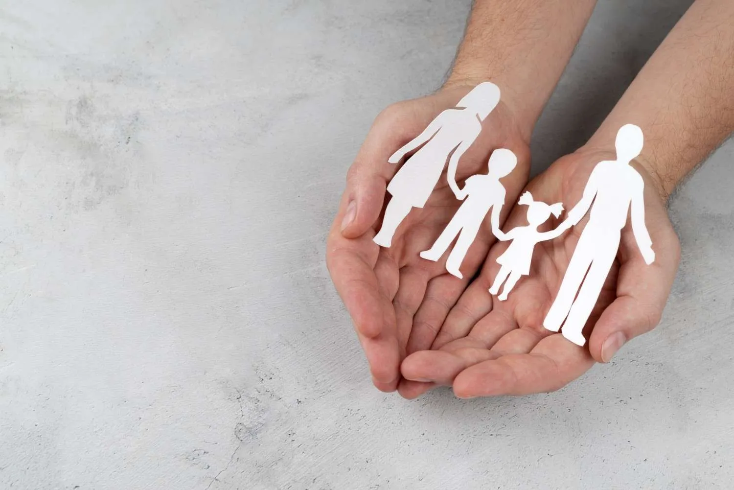 Cupped hands holding a paper cut out of a family